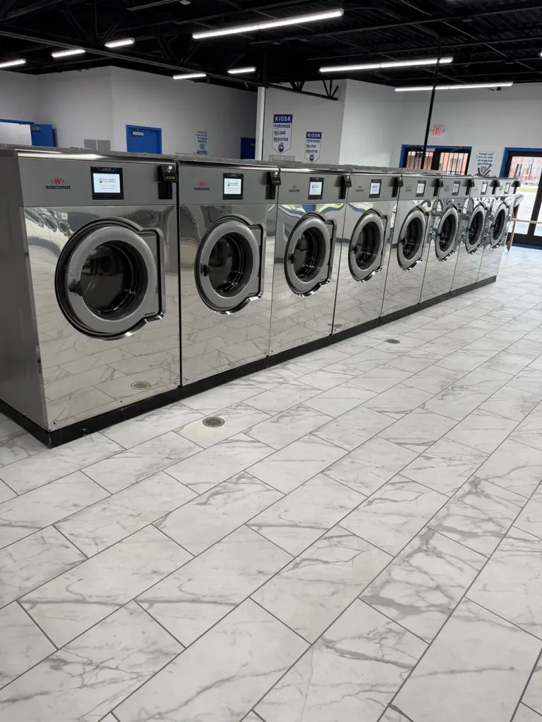 Long line of mirror-finish Wascomat washers on marble-look porcelain tile