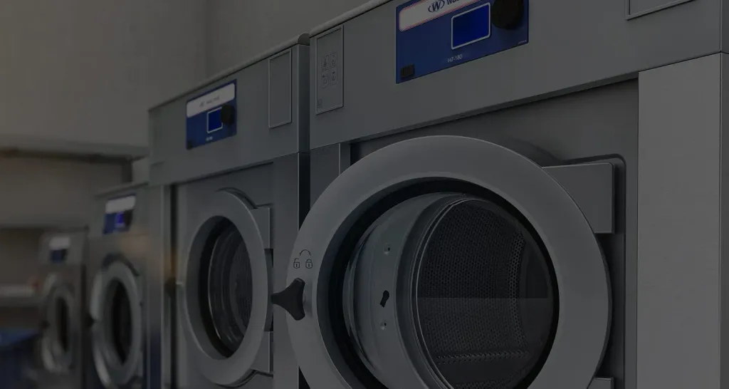 Brightly lit modern laundromat interior with a row of vended washers
