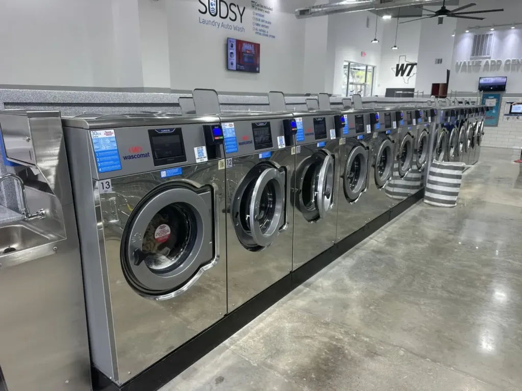 Row of stainless Wascomat washers with ClarusVibe touchscreens under a granite-topped counter