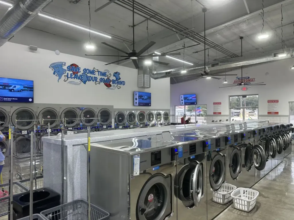 Wide view of the laundromat with stacked dryers, washer island and wall graphics