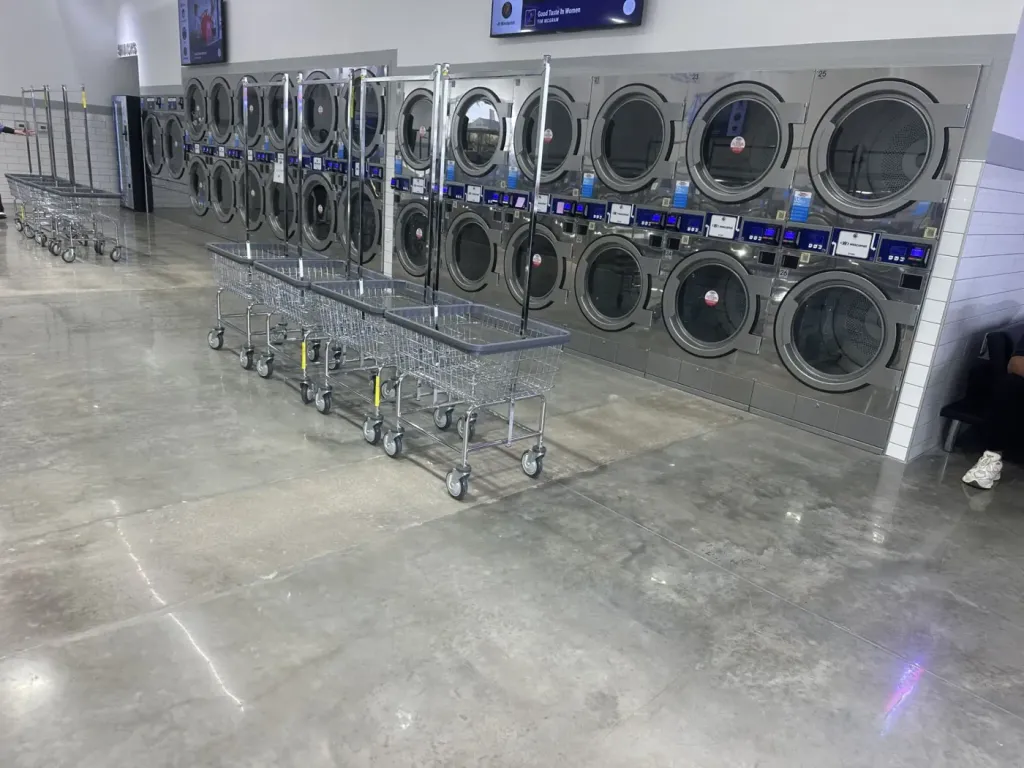 Stacked Wascomat dryer wall with laundry carts on polished concrete