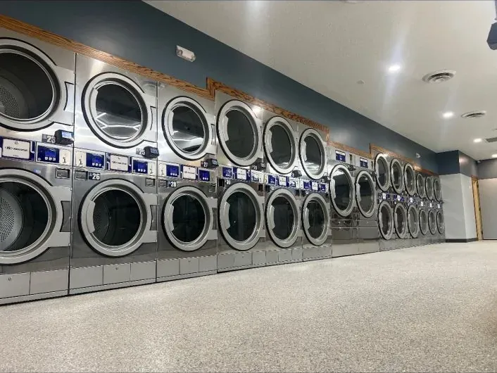 Long wall of stacked Wascomat dryers with timber trim and blue feature wall at the Minnesota Touch store